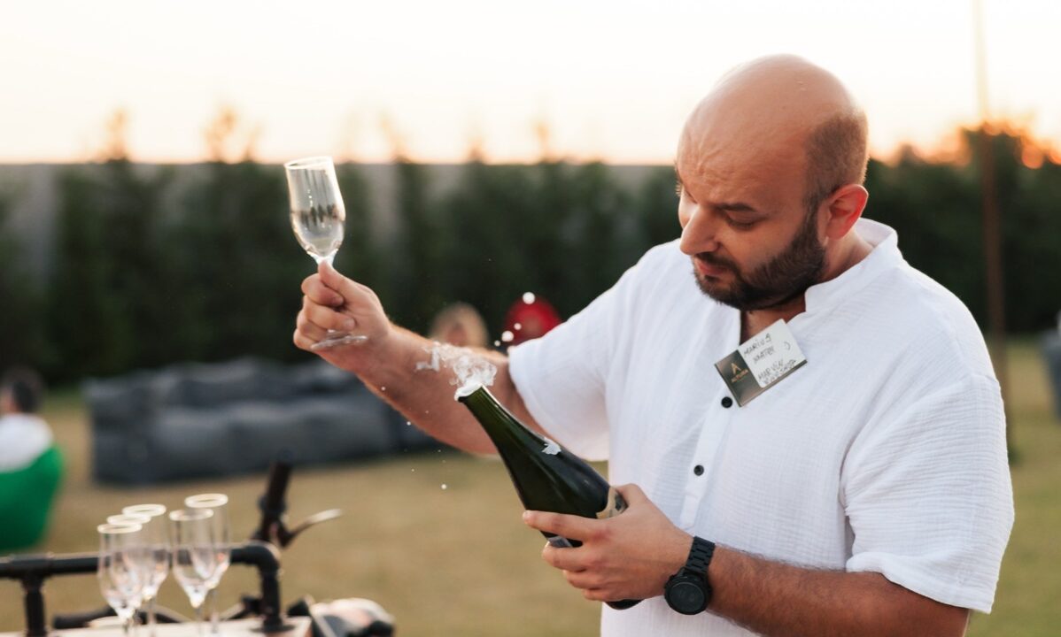 Barman Shaker Bar deschide o sticlă de prosecco lângă moto-bar, la apus